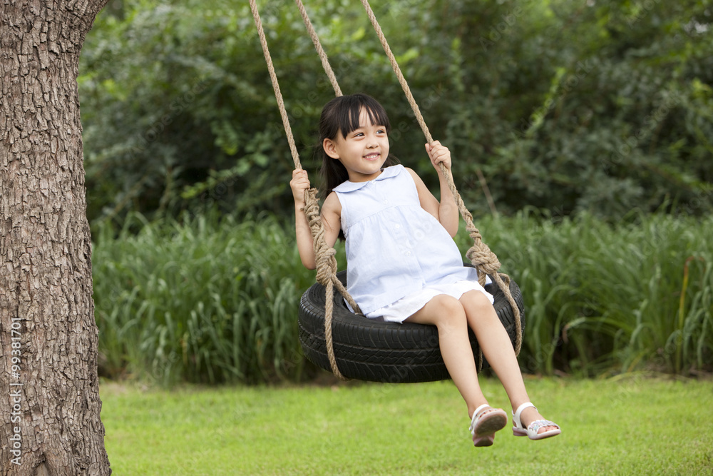 Cheerful little girl playing on a swing