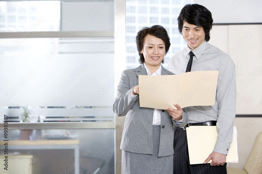 Businesswoman shows employee a file.