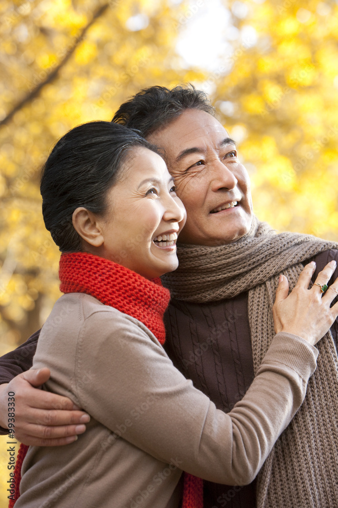 Senior couple embracing and surrounded by Autumn trees