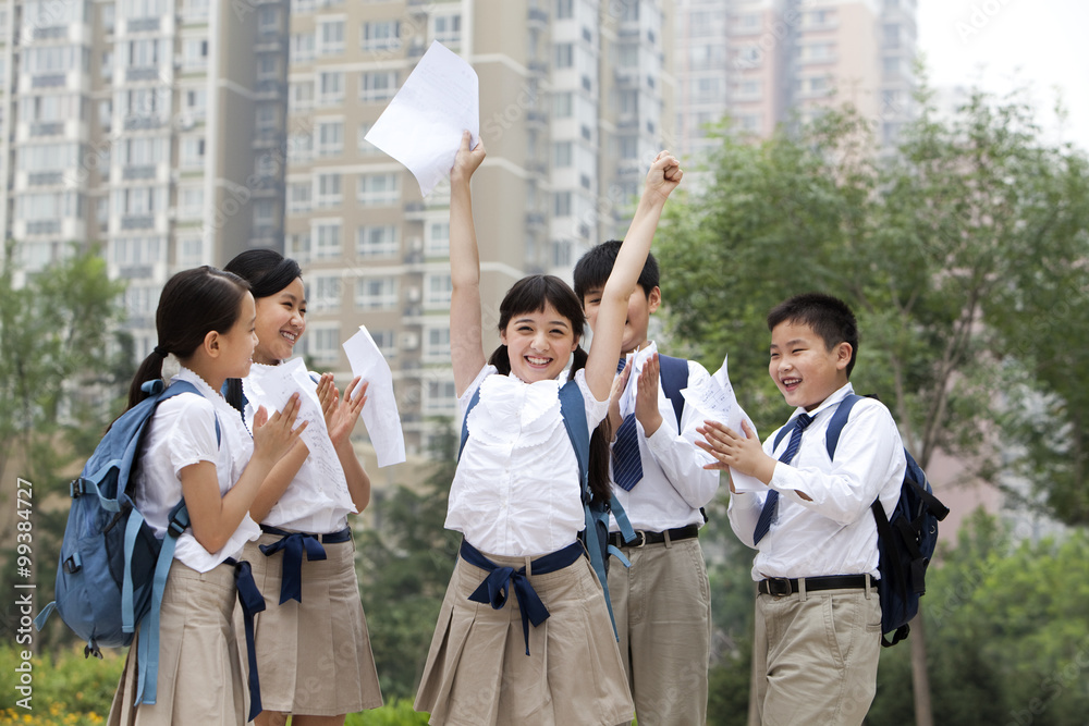 身穿制服的兴高采烈的小学生为他们的考试结果庆祝