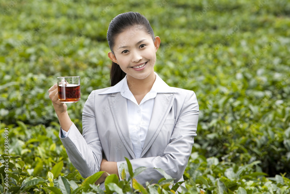 Young Businesswoman in Tea Field with Freshly Brewed Tea