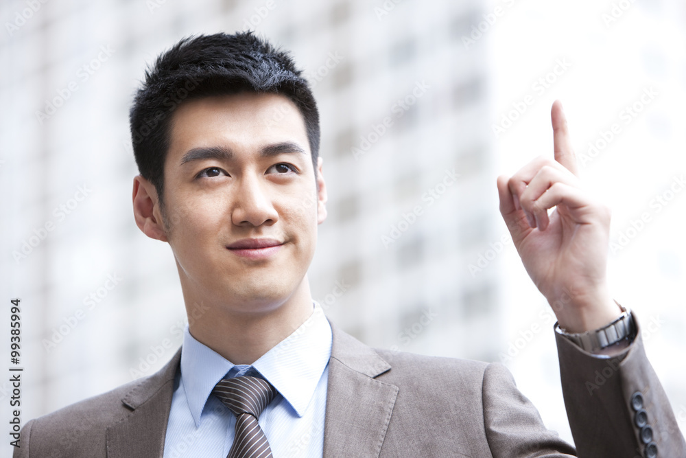 Young businessman pointing up