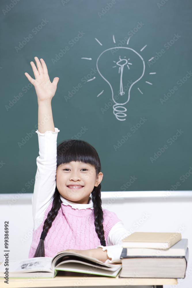 Cheerful schoolgirl raising hand in classroom