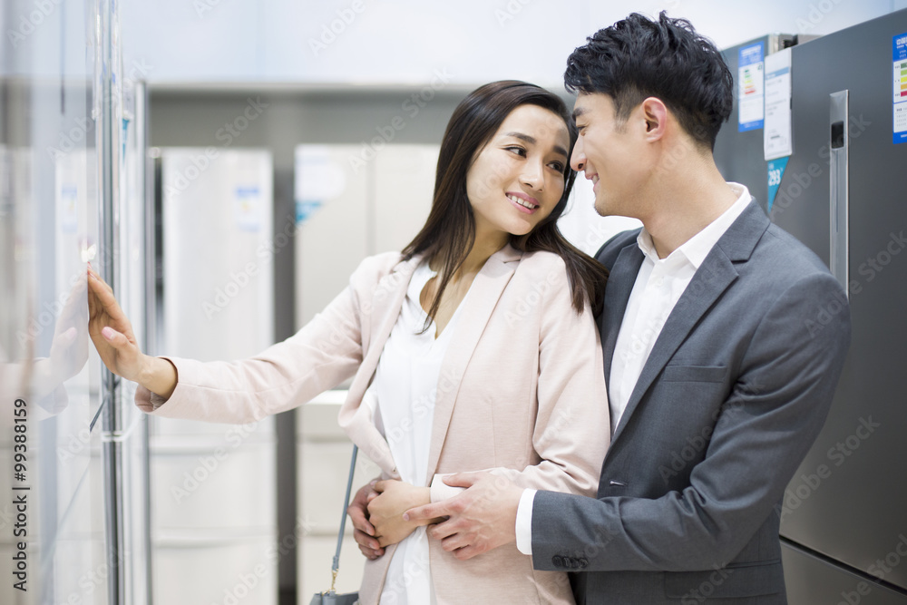 Young couple buying refrigerator in electronics store