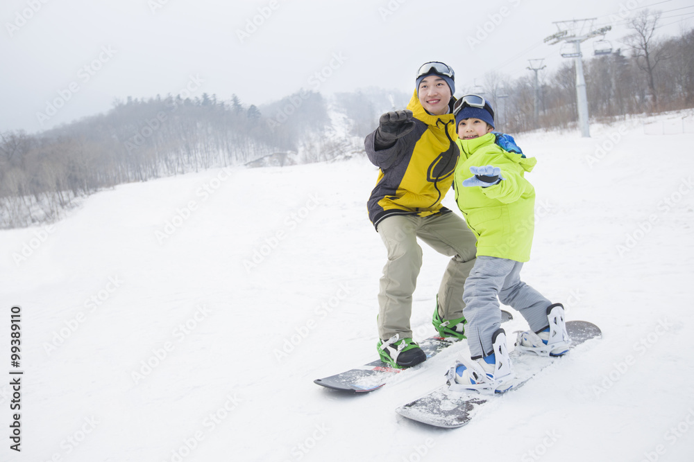 年轻的父亲教儿子滑雪