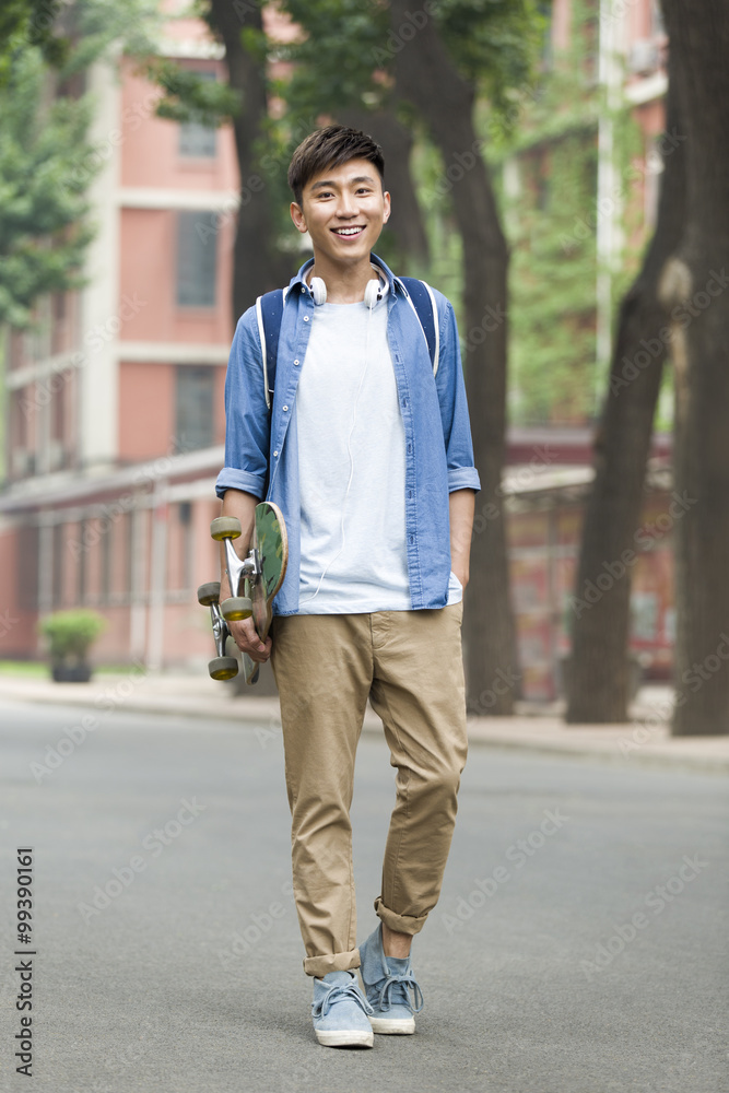 Male college student with skateboard on campus