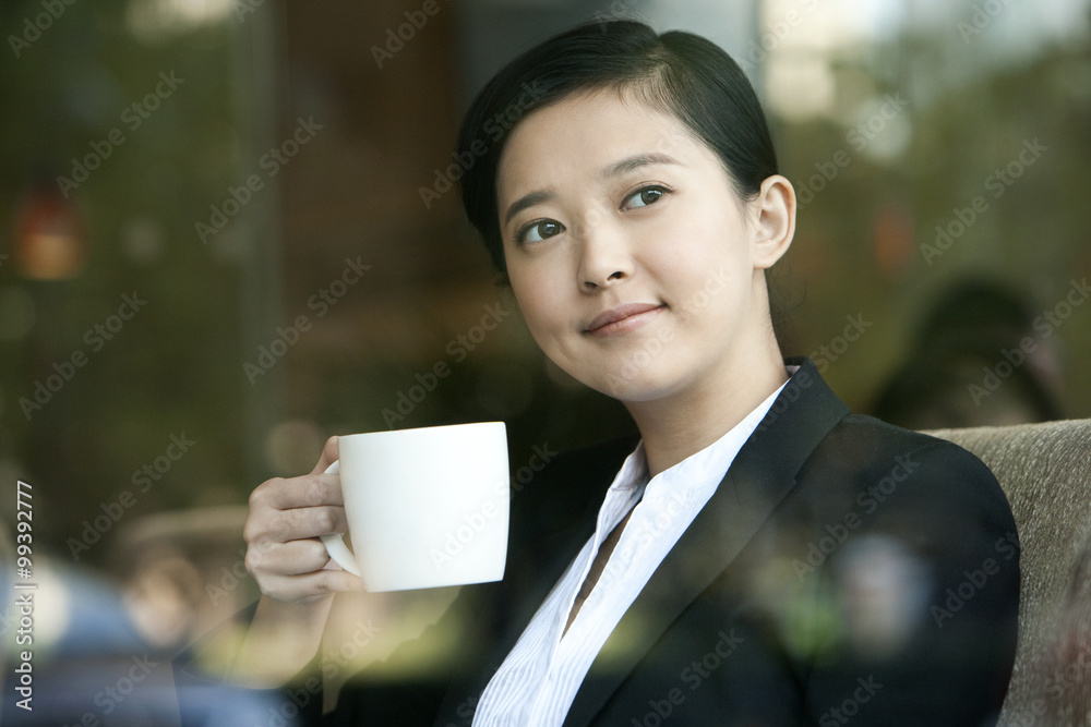 Cheerful businesswoman drinking coffee in cafe