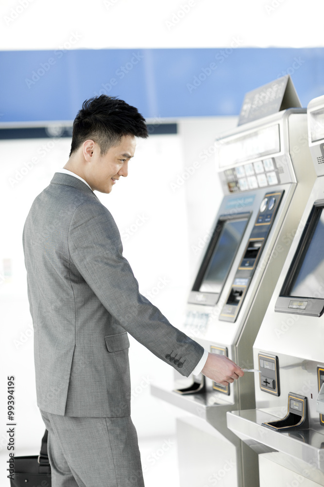 Young businessman using automatic ticket machine at subway station