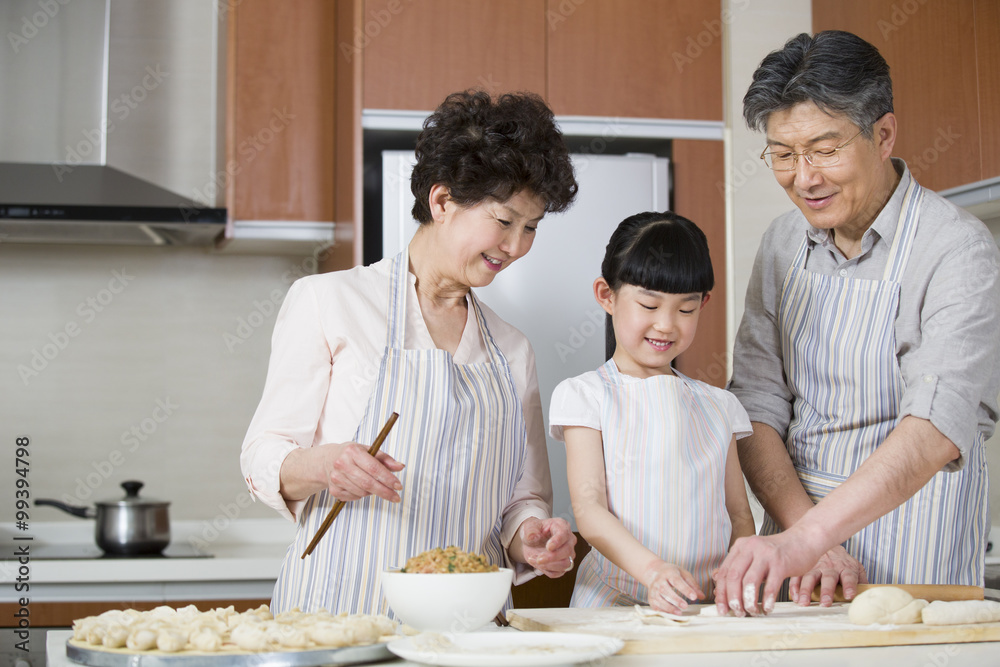 Happy grandparents and granddaughter making dumplings