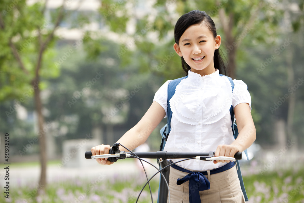 Happy schoolgirl in uniform with bicycle outdoors