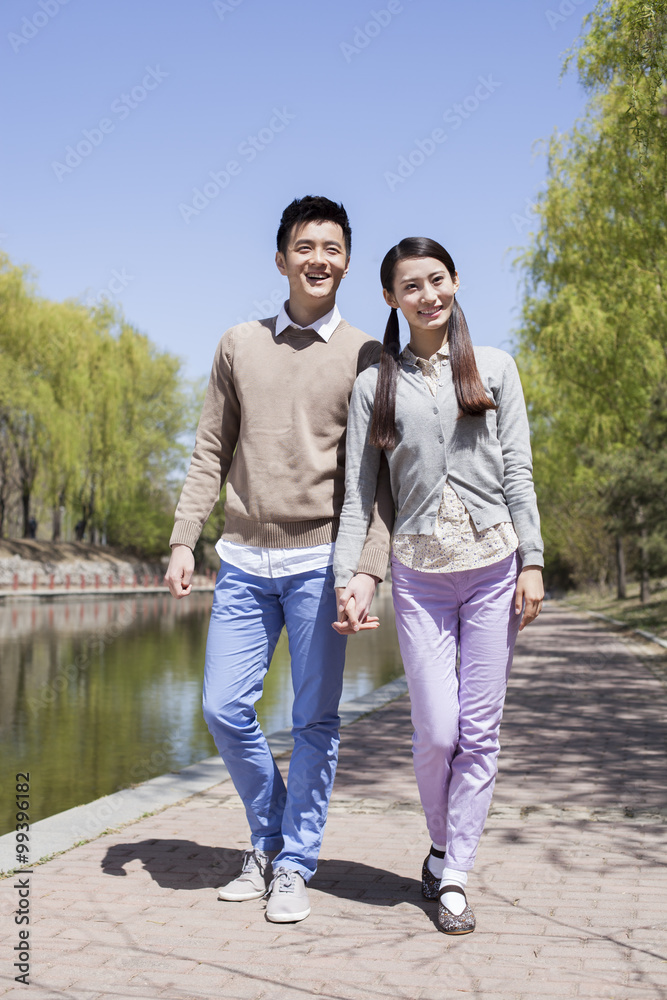 Young couple walking along river hand in hand