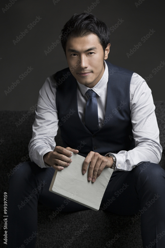 Portrait of businessman sitting against black background