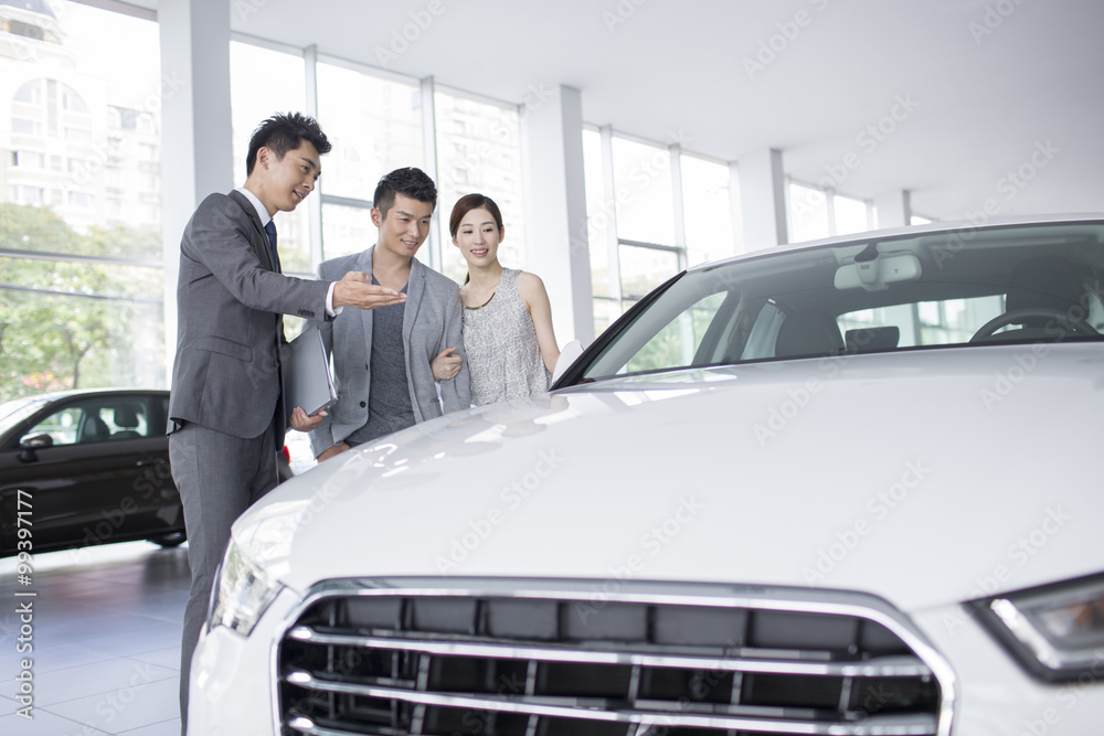 Young couple choosing car in showroom