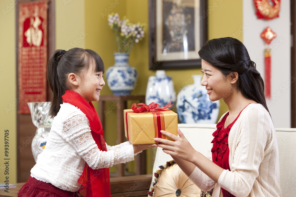 Little girl presenting Chinese New Year gift to mother