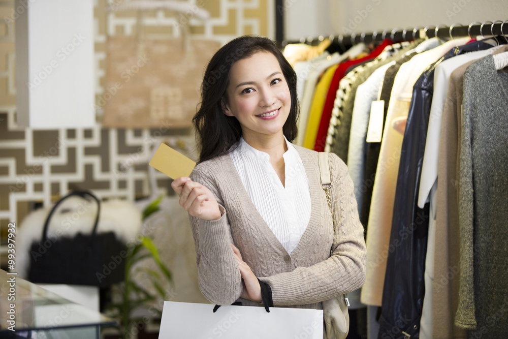 年轻女子在服装店出示信用卡