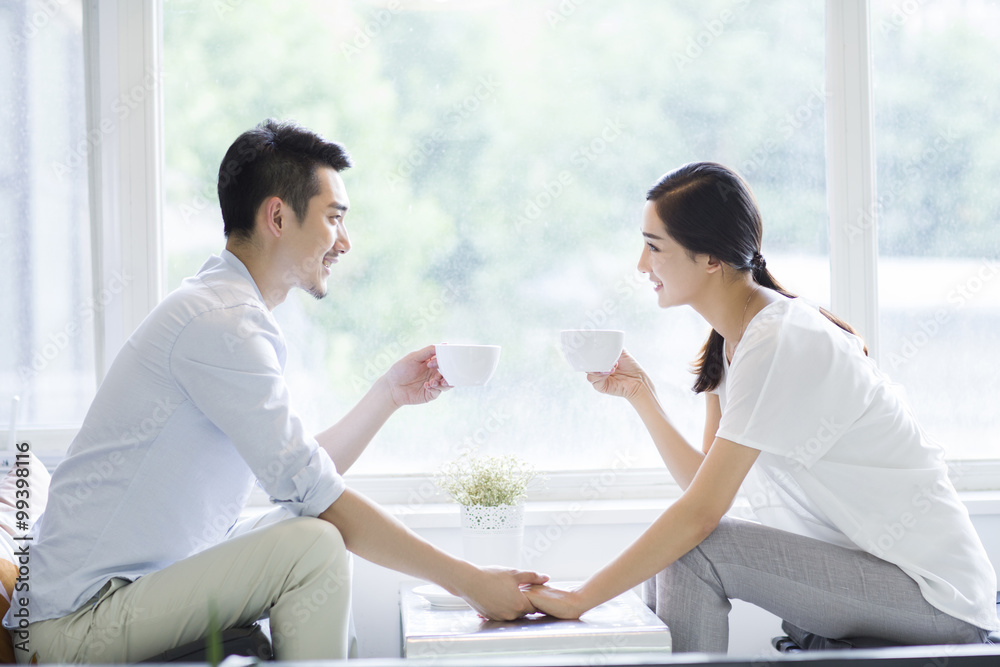 Happy young couple drinking coffee in coffee shop