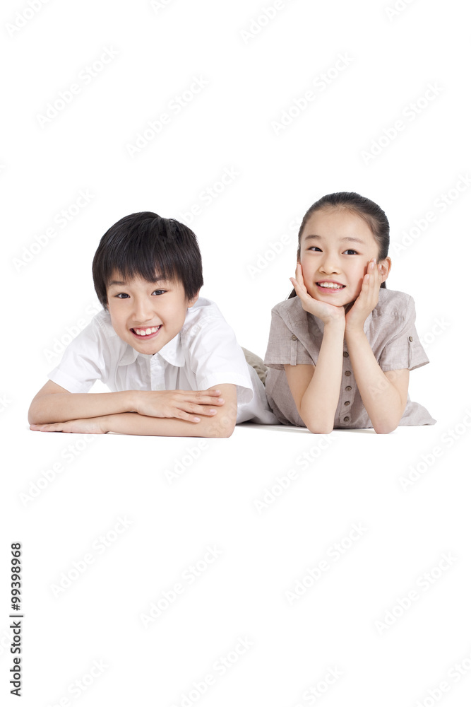 Happy siblings lying on front, studio shot