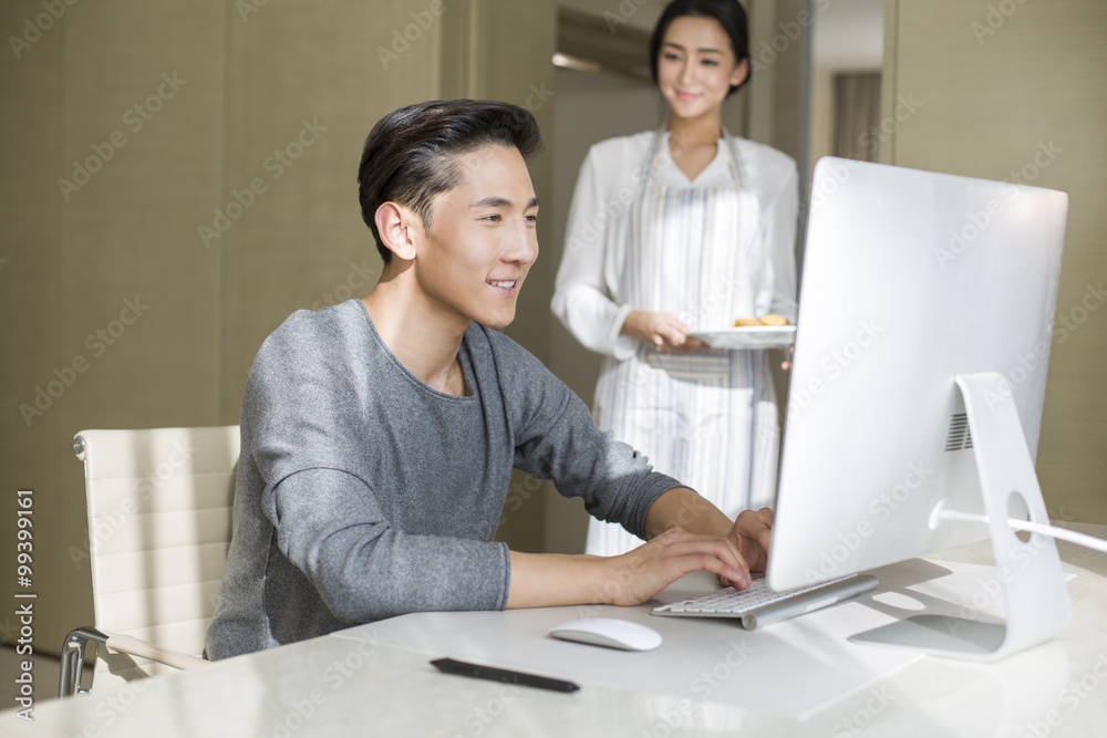 Young man working at home with his wife serving dim sum