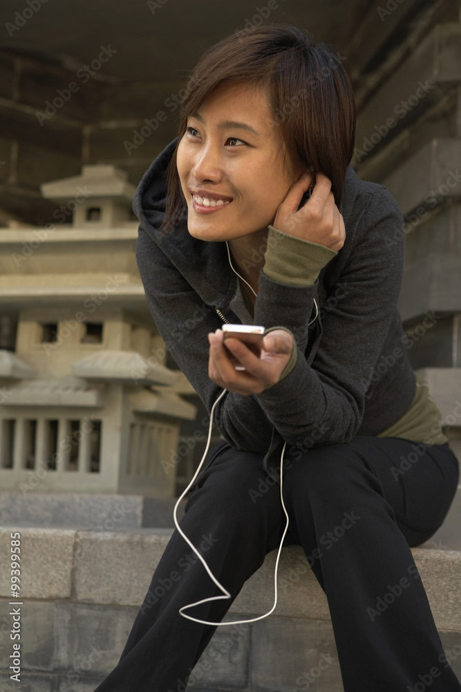 Smiling woman listening  music while sitting outdoors