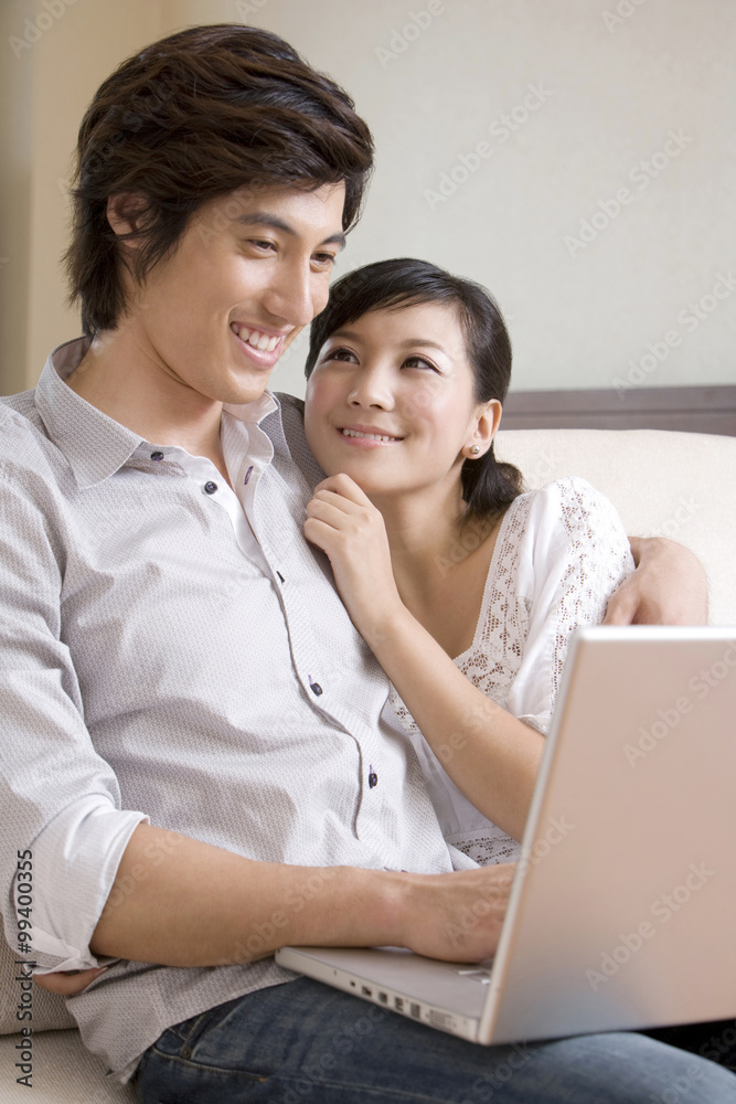 Asian couple cuddling on a sofa