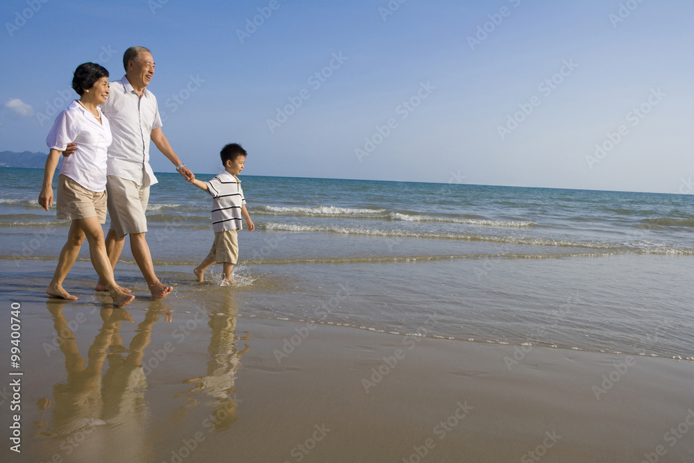  Grandparents and grandson walking along the beach