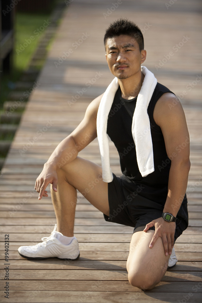 Portrait of young man kneeling on boardwalk