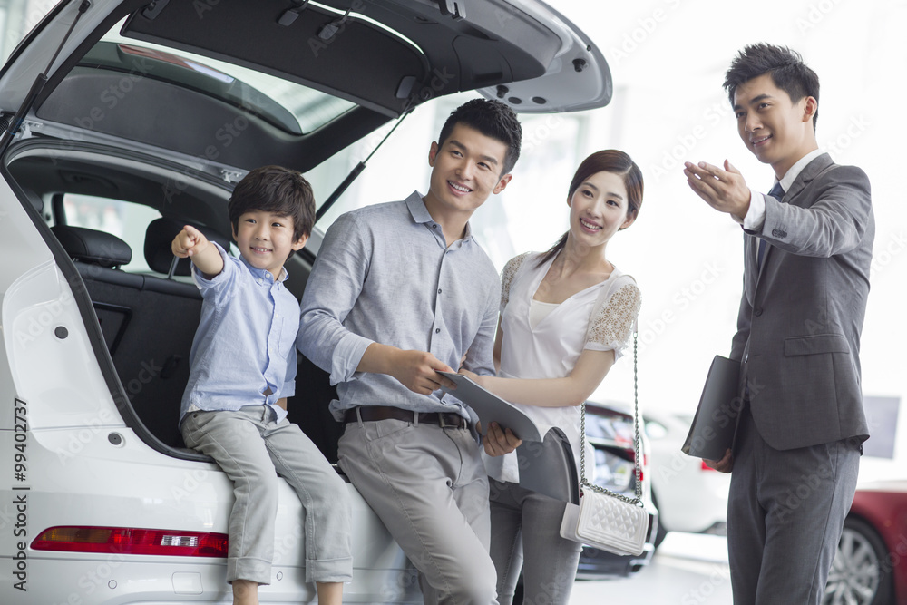 Young family choosing car in showroom