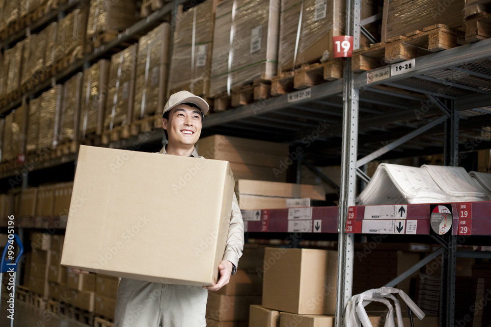 Male Chinese warehouse worker carrying boxes