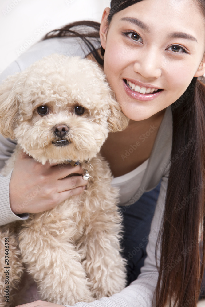 年轻女子与宠物玩具贵宾犬玩耍