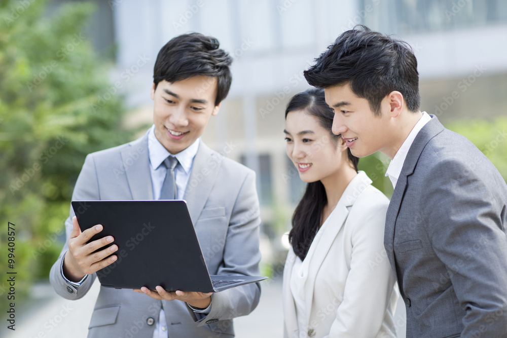 Young business person working with laptop outdoors