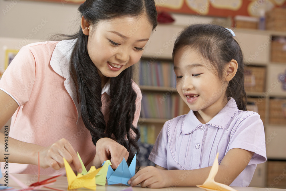 老师和年轻女孩制作折纸鸟