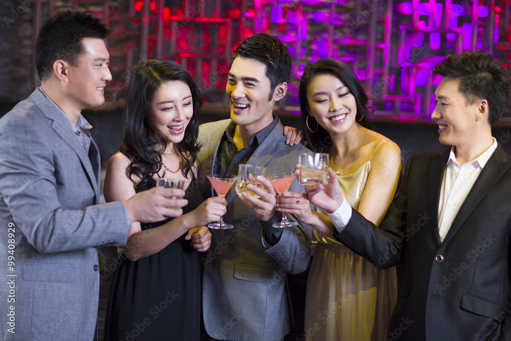 Young friends toasting at bar