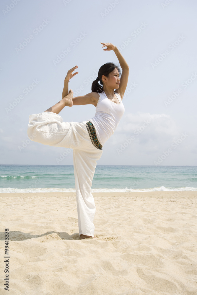 Young woman doing yoga on the beach