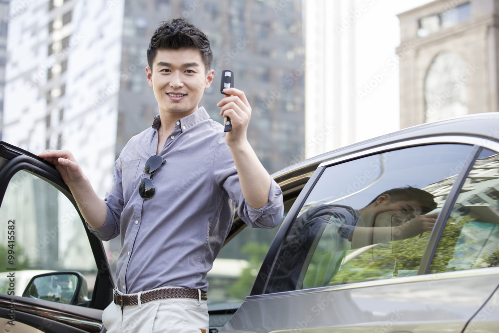 Young man posing with keys to his new car