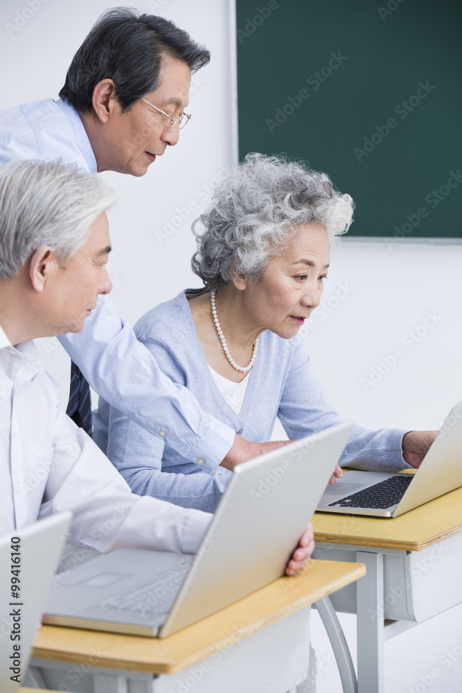 Senior adults having computer class at school