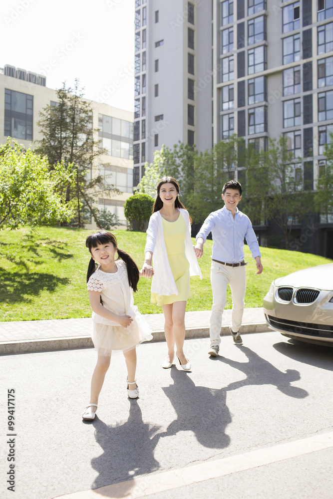 Happy young family holding hands walking