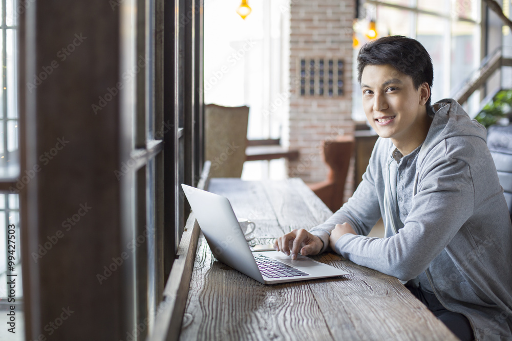 Young man using laptop in cafe