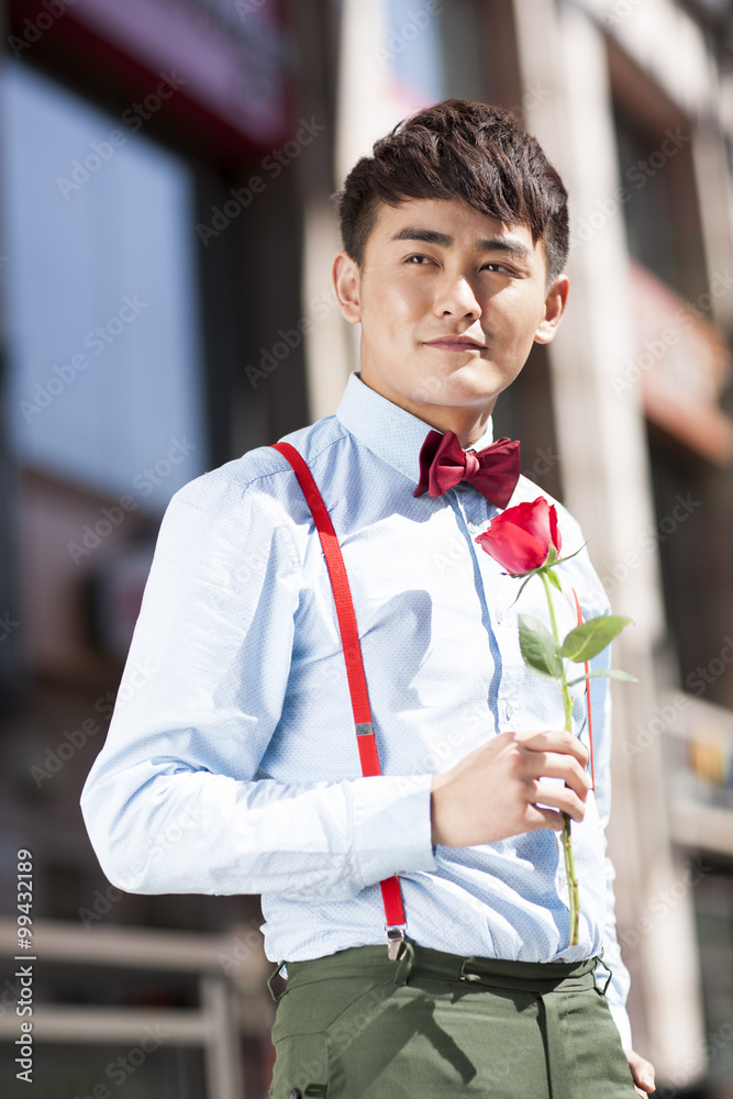 Stylish young man with rose in hand