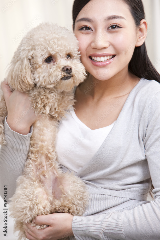 年轻女子与宠物玩具贵宾犬玩耍