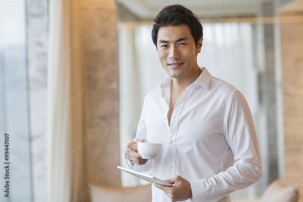 Young man drinking coffee with digital tablet