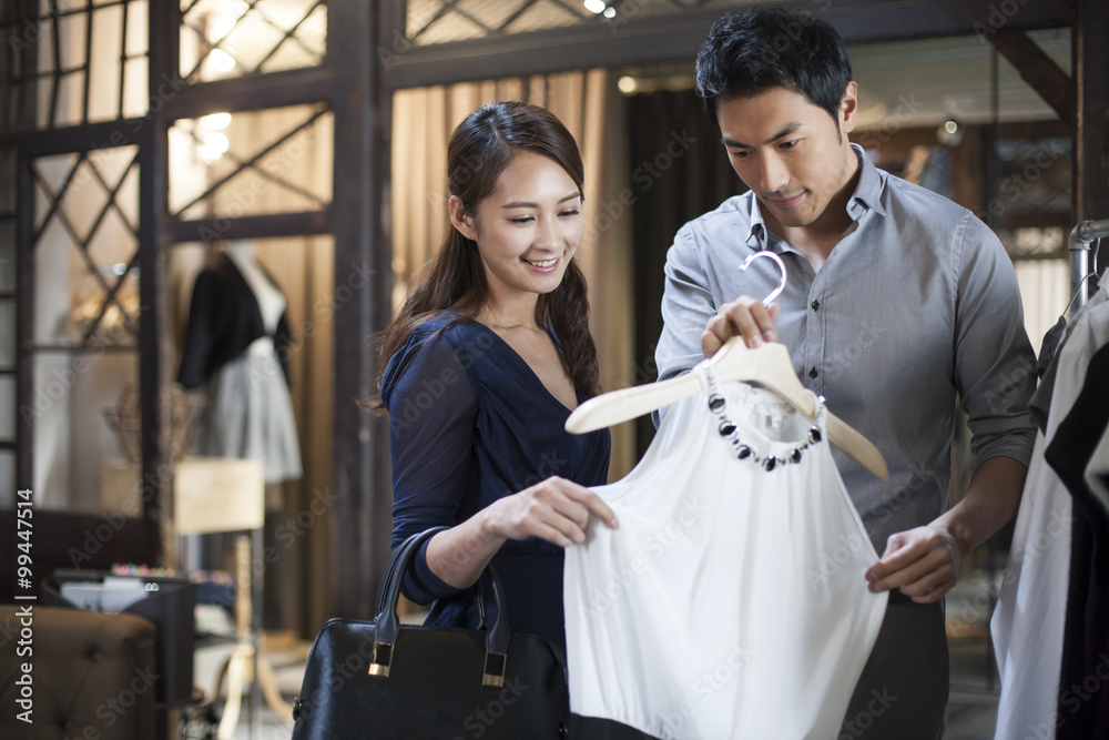 Young couple choosing dress in clothing store