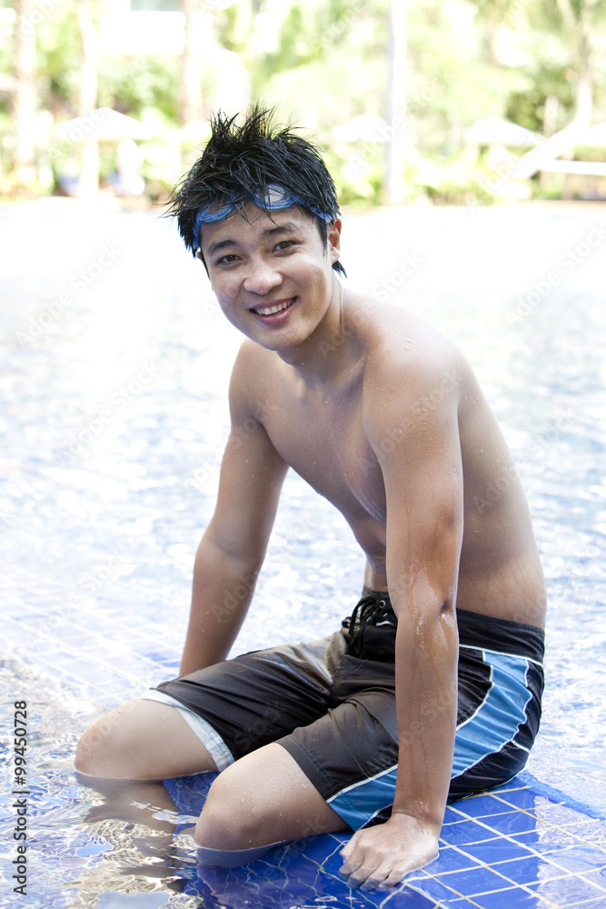 Portrait of a young man sitting poolside