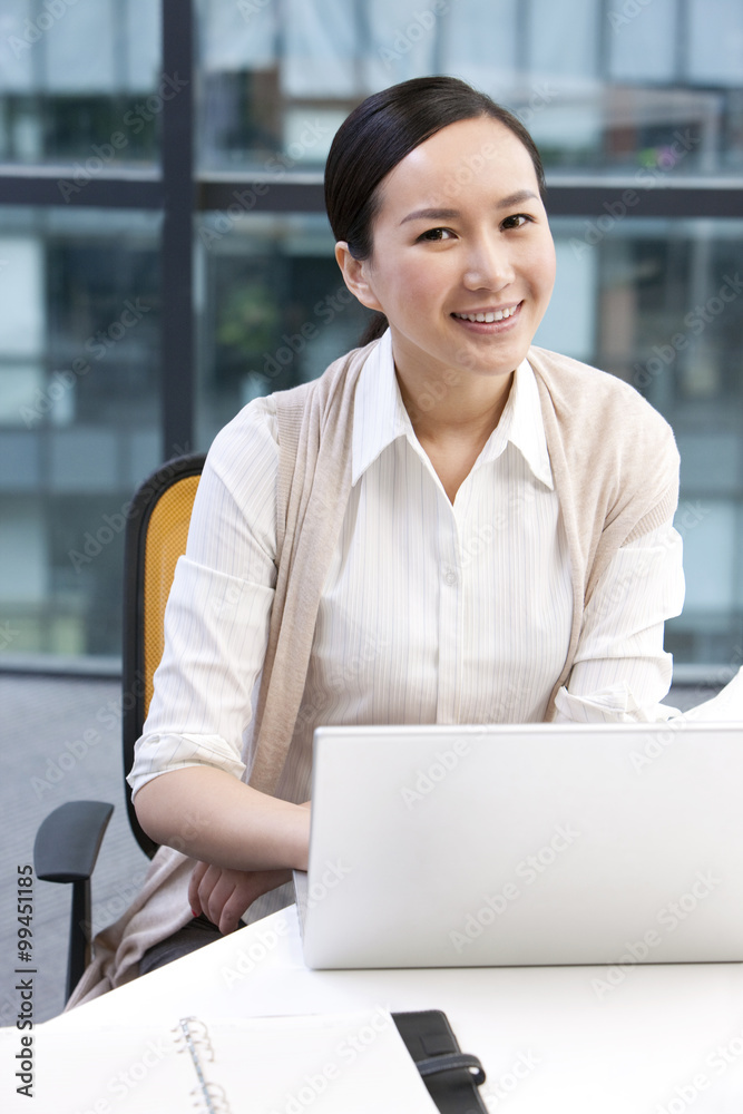 Businesswoman sitting with a laptop and a notebook