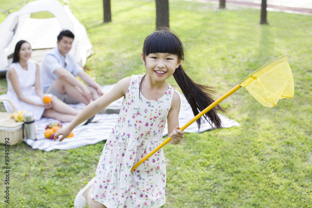 Happy girl playing on grass with butterfly net