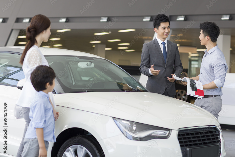 Young family choosing car in showroom