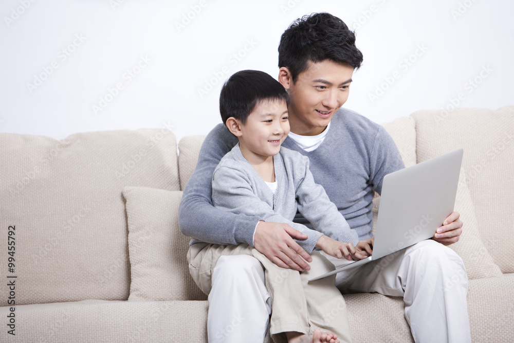 Happy father and son using laptop at home