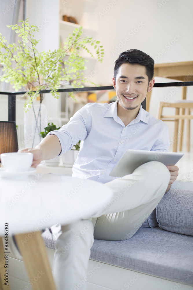 Happy young man using digital tablet in coffee shop