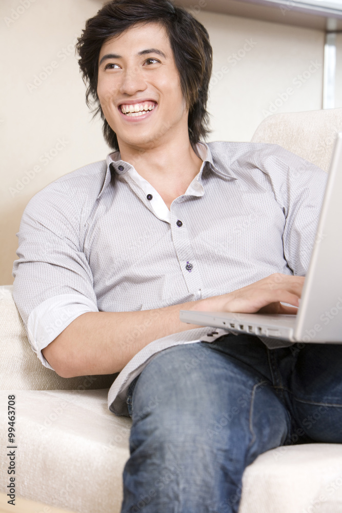 Asian man on sofa with laptop