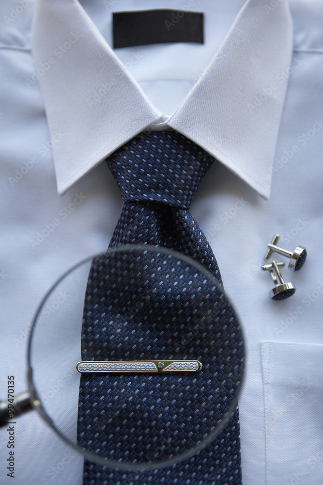 A Magnifying glass focused on a tie clip on a neck tie