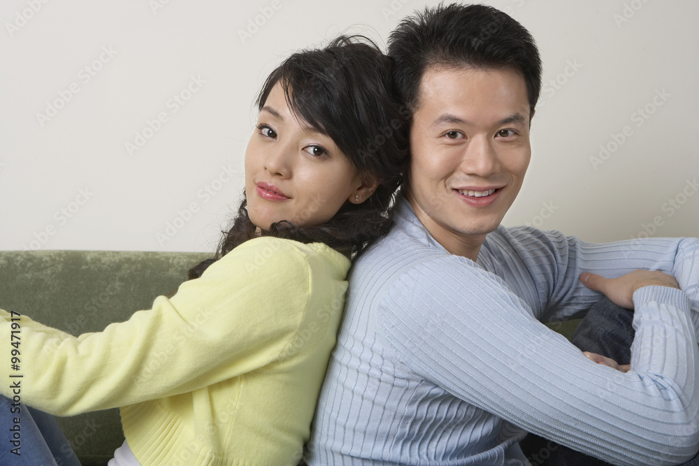 Young People Sitting Back To Back On Couch